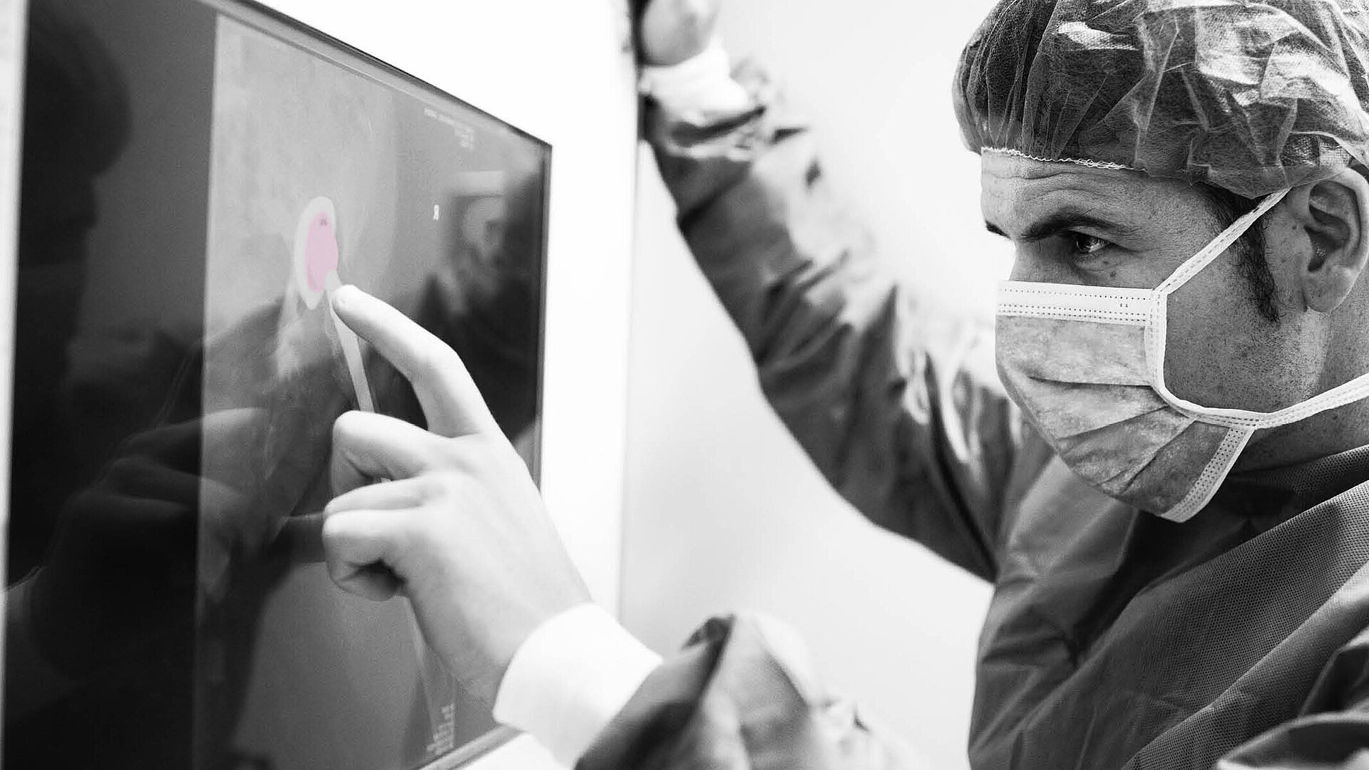 A mainly black and white image of a surgeon examining an x-ray where a pink BIOLOX®delta femoral head is highlighted