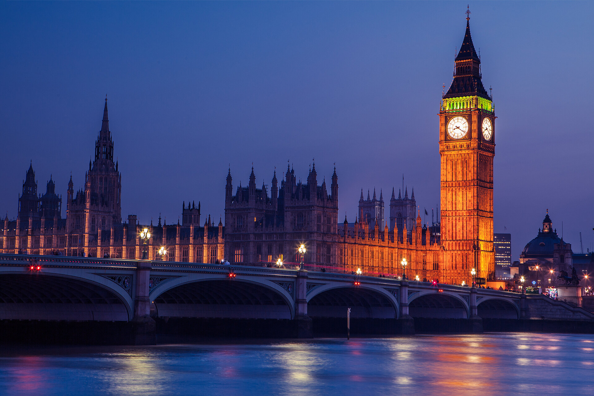 Elizabeth Tower and the Houses of Parliament beside the River Thames at dusk.