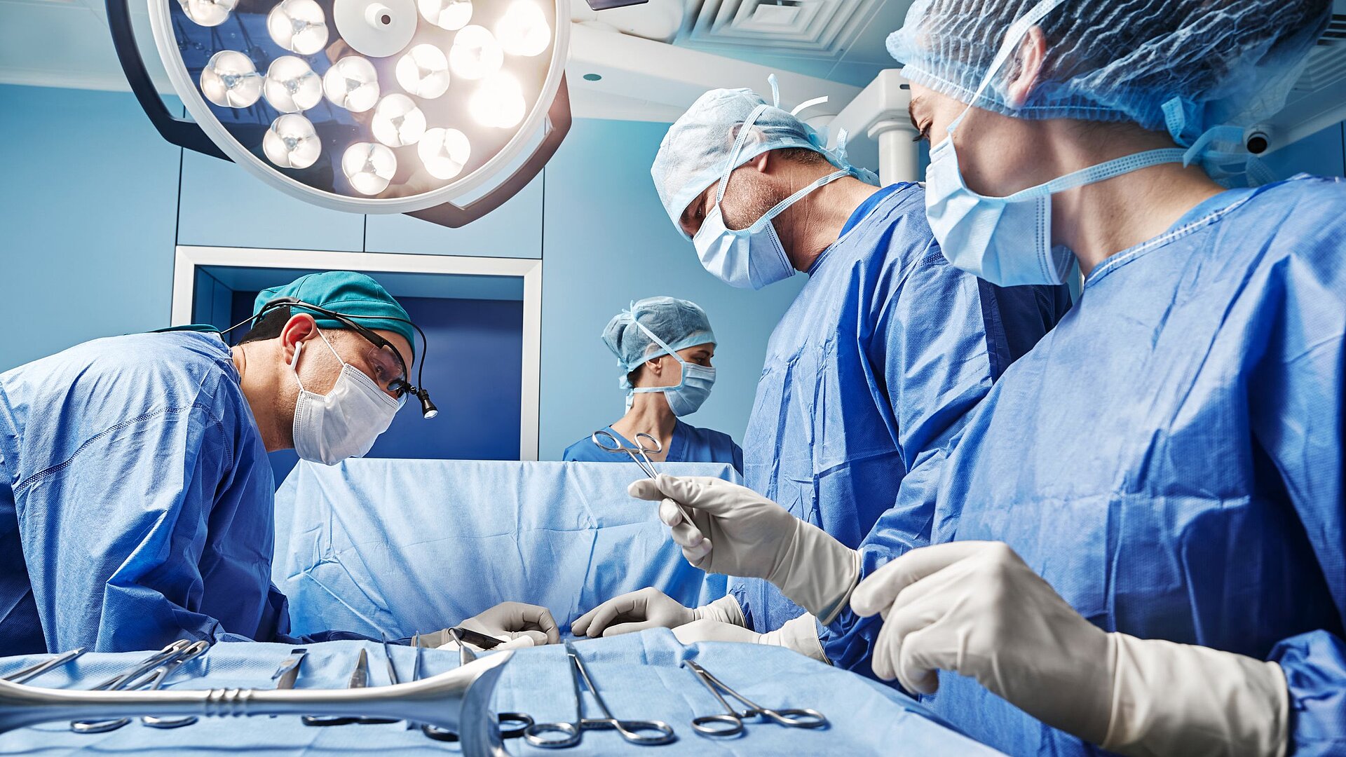 Four doctors working in an operating room, surrounded by modern specialized equipment.