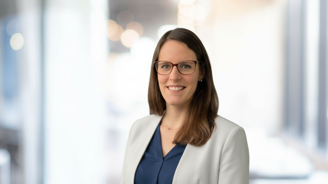 Yvonne Mödinger im weißen Blazer und dunkelblauer Bluse vor hellem Büroflur