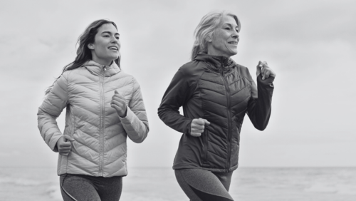 BIOLOX® | The picture shows two people running on the beach. They are both wearing sports clothes. The background shows a cloudy sky and the sea, indicating cooler weather. It is in black and white, which makes it look active and healthy.